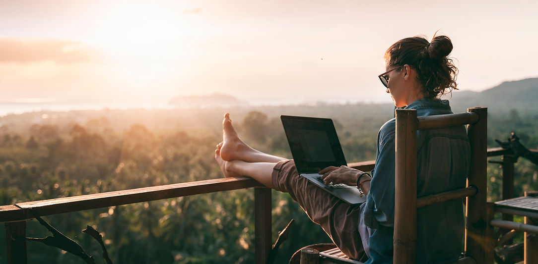 Woman working on a laptop on her deck at sunset
